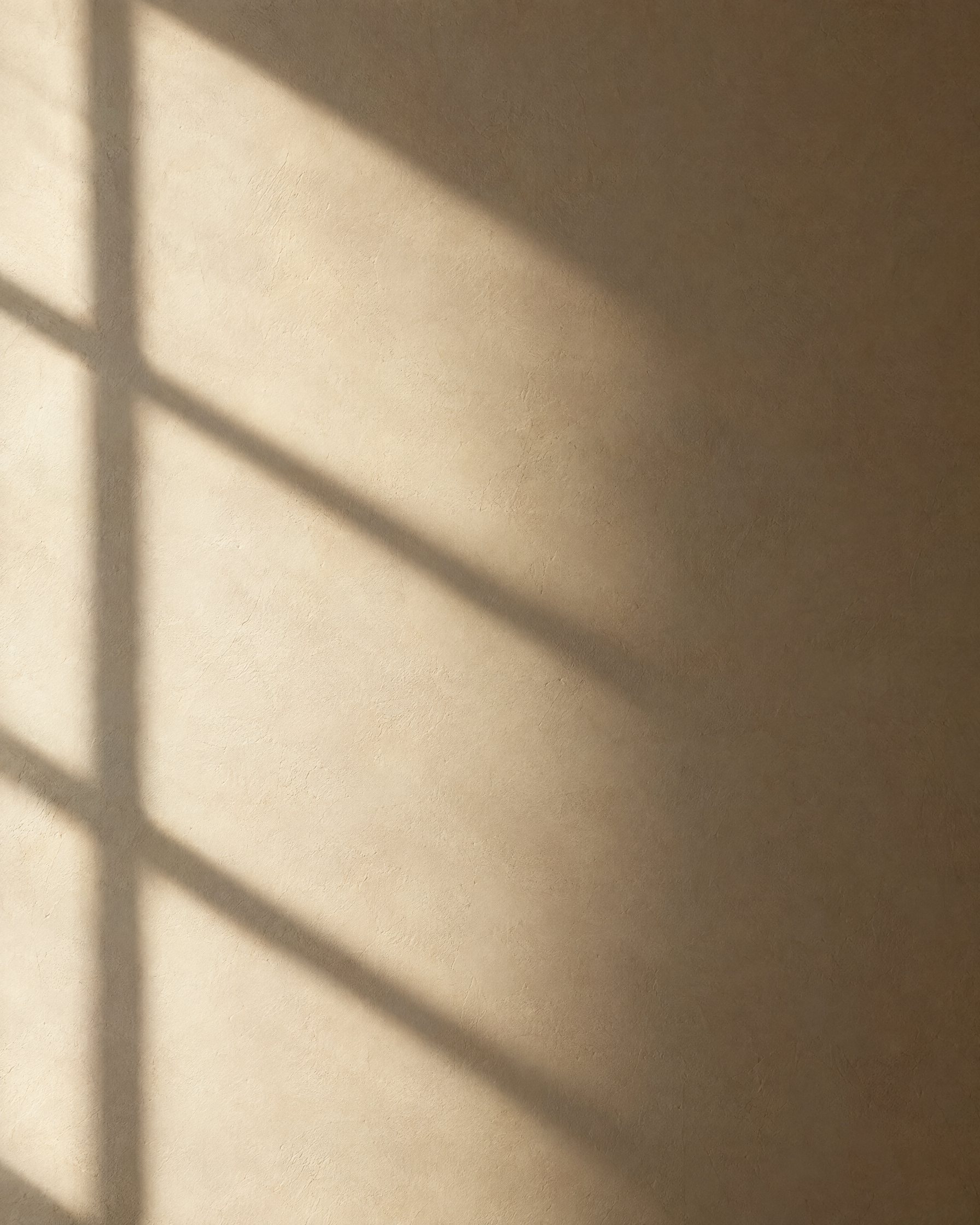 Sunlight and a window shadow moving across a plaster wall